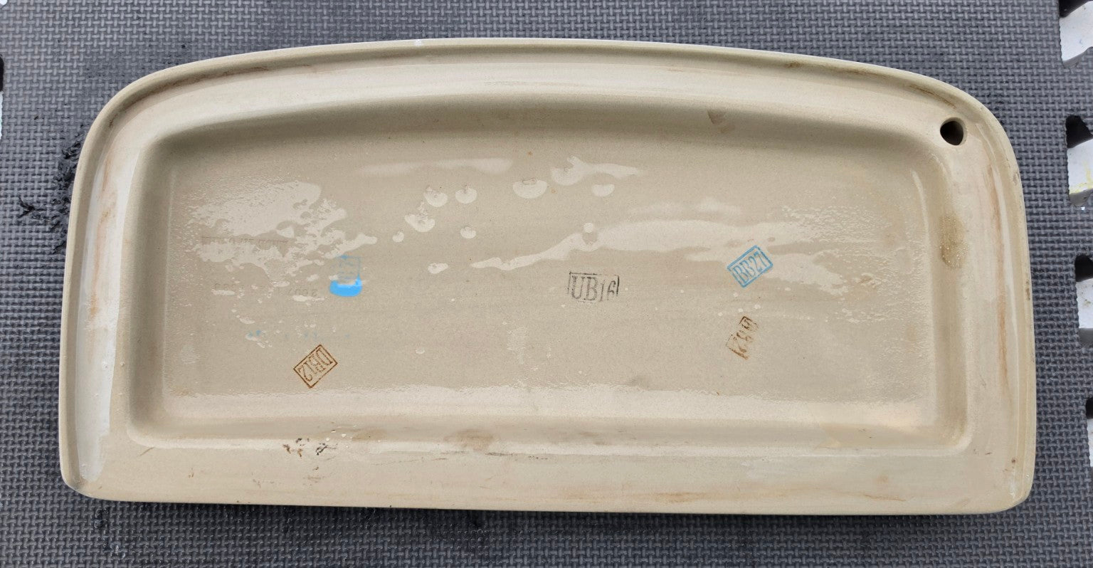 Underside of original Glacier Bay 140-911 MLS10012 white toilet tank lid showing corner vent hole and seating rim